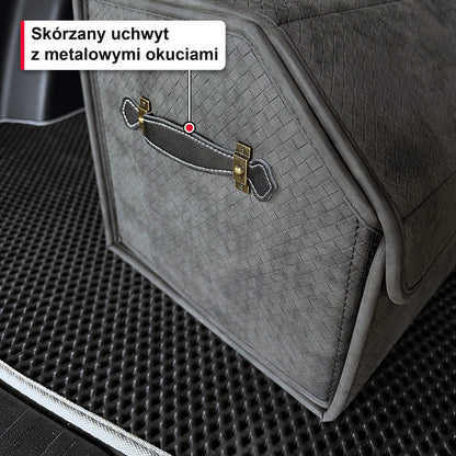 Zbliżenie na skórzany uchwyt z metalowymi okuciami na szarym organizerze do bagażnika